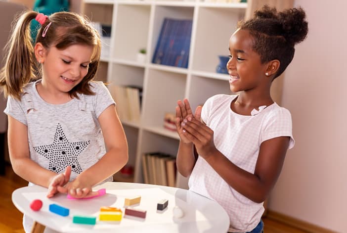 Two Children Playing Together At A Classroom Table