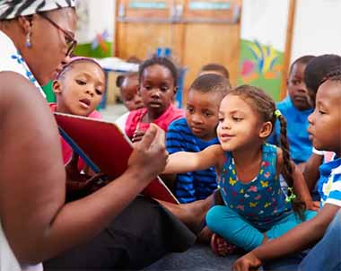Teacher Reading A Book With Young Children